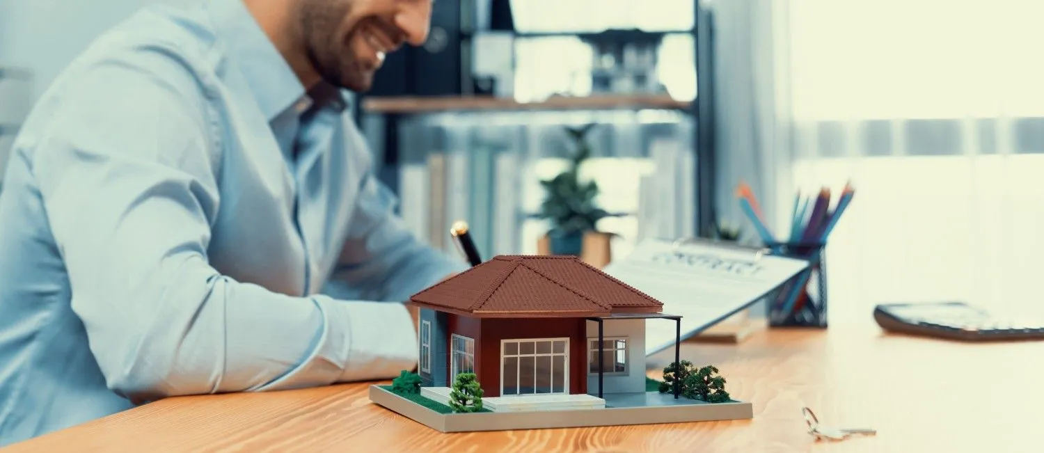 Homeowner going over cover at a desk with a model house and keys