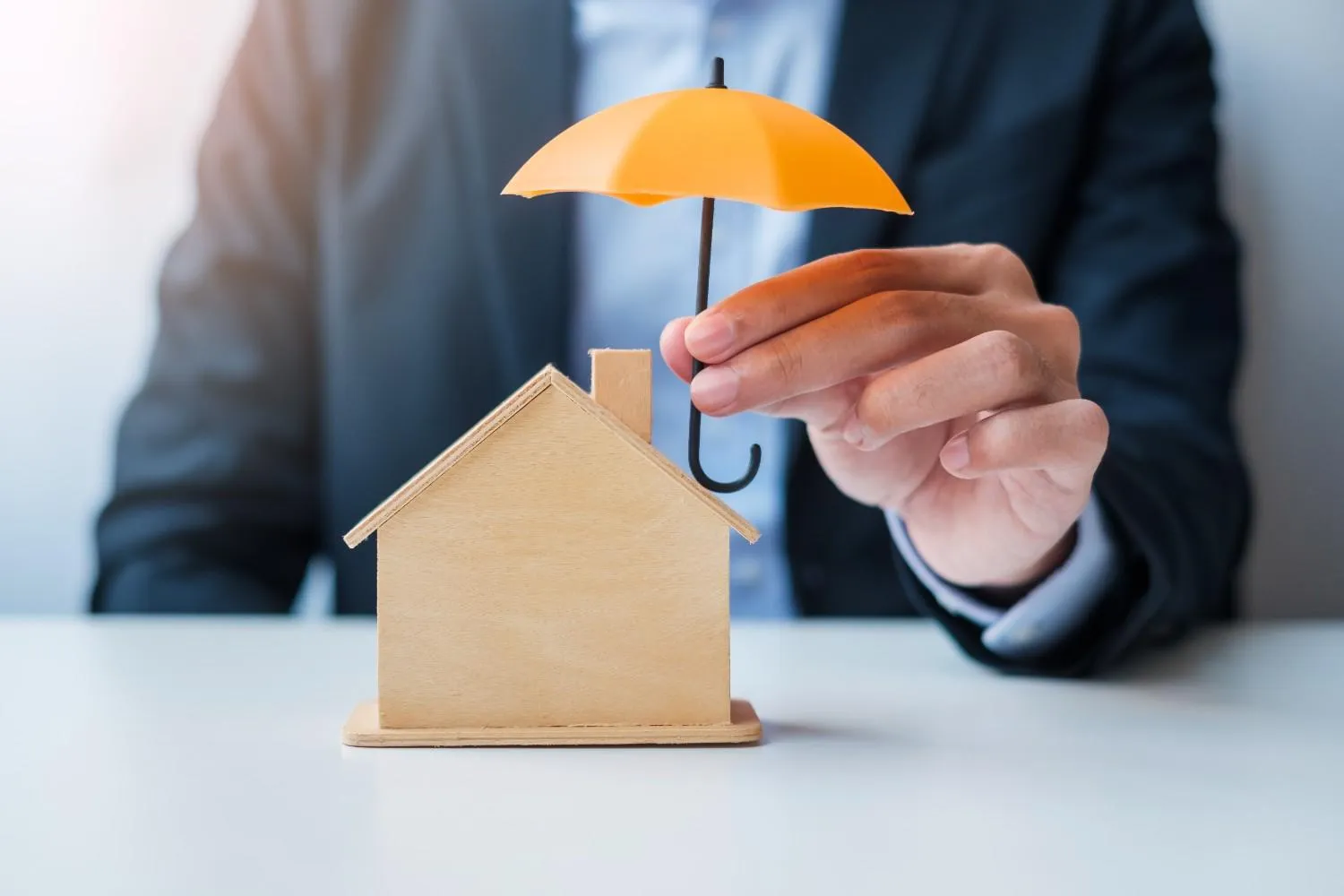 Umbrella held over a small wooden house